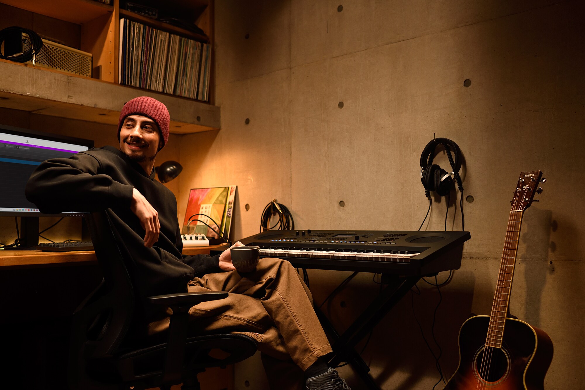 A home music workspace with a computer and keyboard, featuring a keyboardist working in their home studio