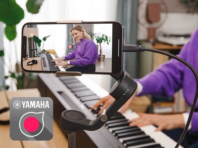 Вид на значок приложения Yamaha Rec'n'Share и человек, снимающий на смартфон видео, как он играет.
