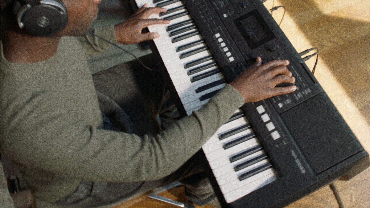 A person playing Yamaha Portable Keyboard PSR-E483 with headphones